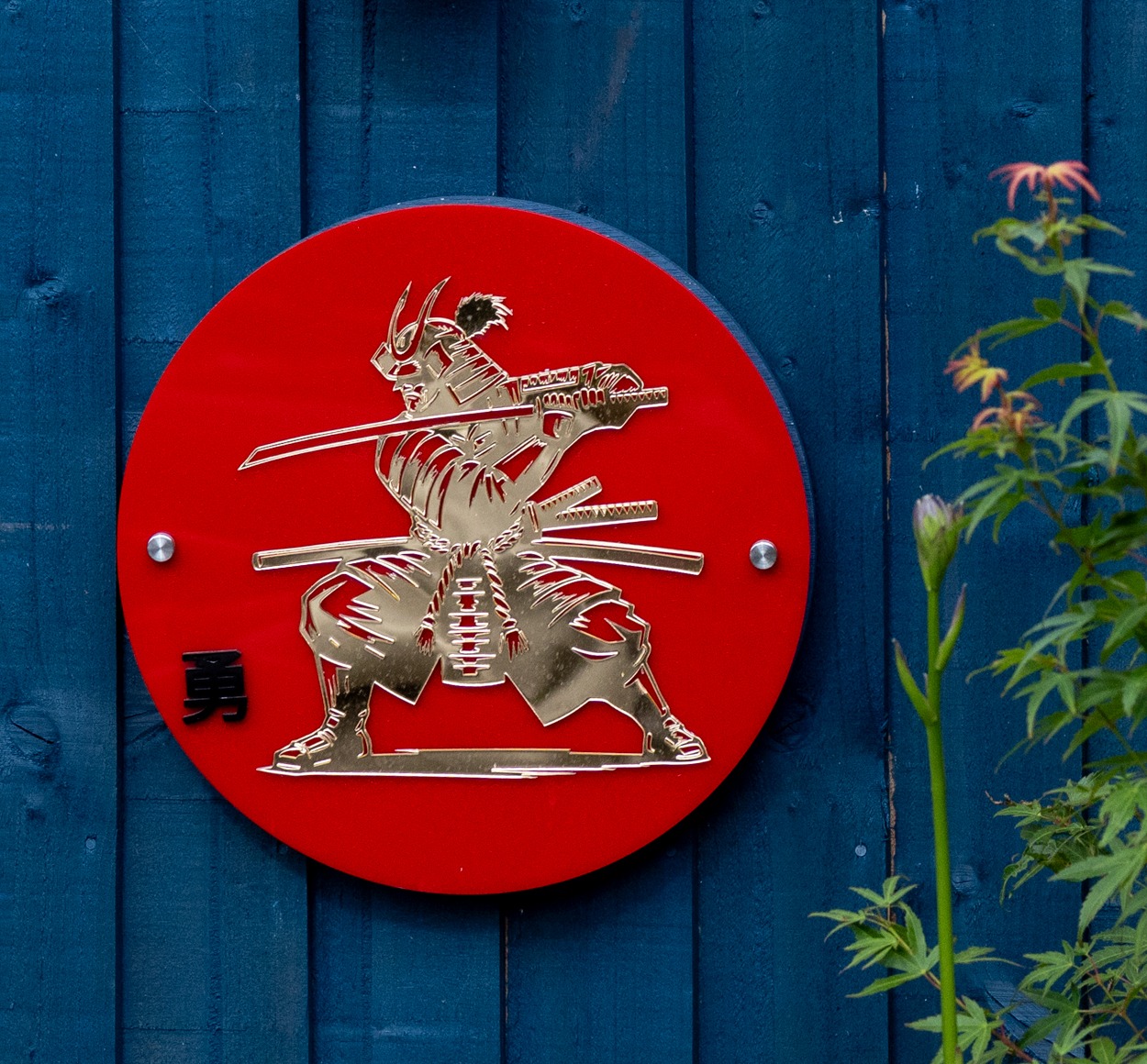 Red circular samurai plaque with metallic laser-cut figure