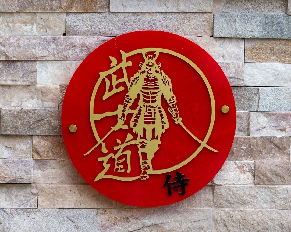 Red and gold Samurai Warrior wall plaque displayed on a stone wall
